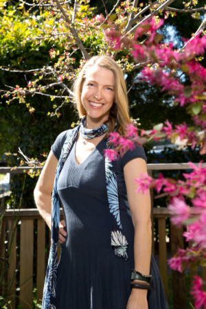 Smiling woman in blue with pink flower in foreground