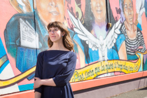 Teacher poses in front of a mural