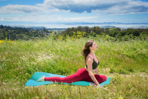 Yoga instructor doing pigeon pose in a field
