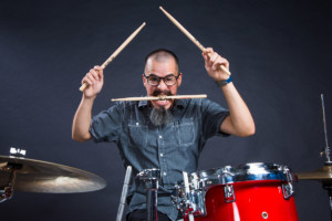 Wild drummer with drumstick in mouth